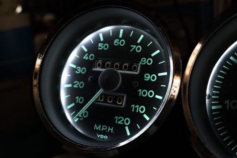 Speedometer lit from behind in the dashboard, green numerals reading to 120 mph, VDO on the dial, a second gauge alongside.